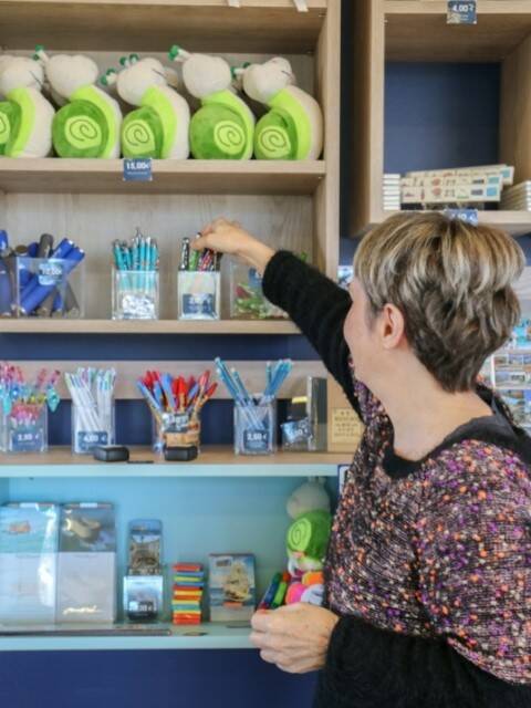 Ursula, Reiseberaterin vor den Regalen im Laden